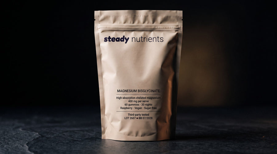 A pouch of Steady magnesium gummies on a bedside table beside a lamp